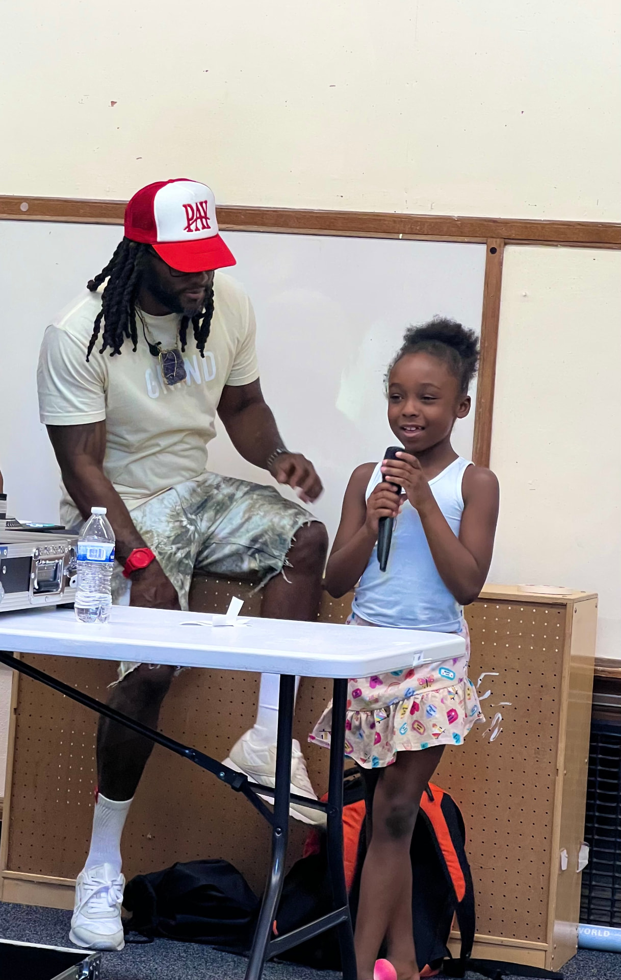A young student sharing on the microphone while a facilitator encourages her